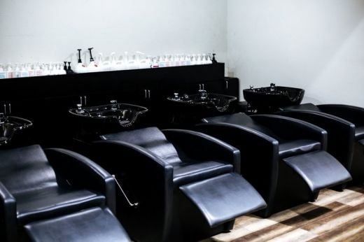 RIO G-046 shampoo backwash unit with near-flat reclining chair and kick-out footrest, black upholstery, white stationary ceramic bowl with built-in headrest and gel neckrest